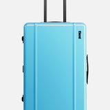 The FLOYD Check-In Suitcase is a bright blue hard-top case with a TSA lock, black handle extended upward, and four red 360° spinner wheels, shown upright against a plain white background.