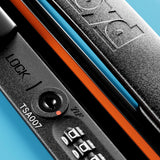 Close-up of The Check-In Suitcase by FLOYD, featuring a hard-top lock with an embossed handle, TSA007 keyhole, combination dials, and an orange accent—shown against a vibrant blue background.