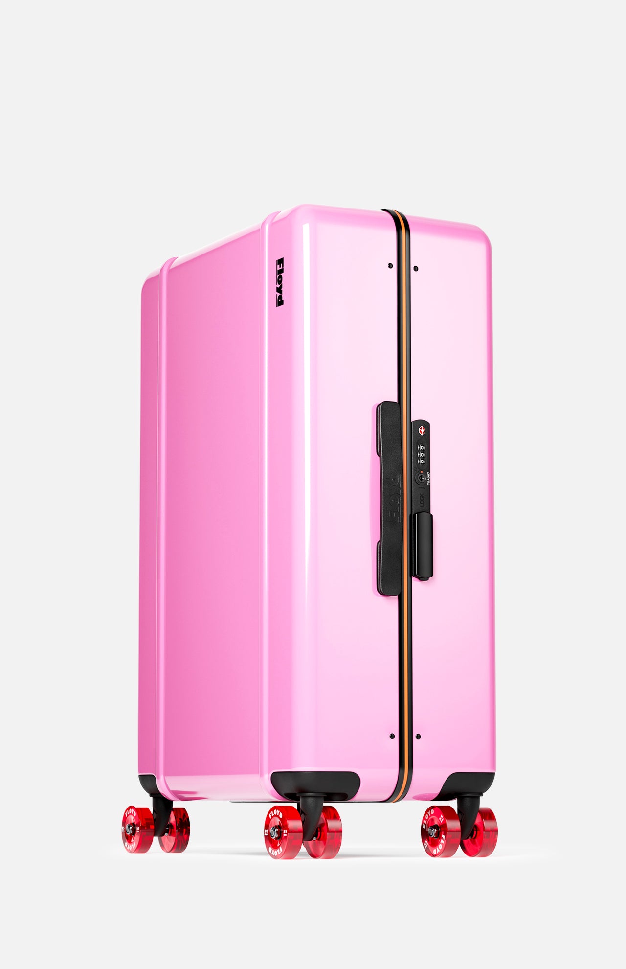 The Check-In Suitcase by FLOYD features a pink hard shell, black handles, a vertical black and yellow stripe, TSA lock, and four red transparent 360° spinner wheels. Shown on a plain white background.