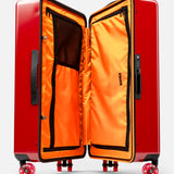 The FLOYD Check-In Suitcase stands upright with its hard red shell open to showcase a vibrant orange interior featuring mesh zippered compartments and a built-in TSA lock on the side. Designed for smooth mobility, it comes equipped with four skateboard spinner wheels and sturdy black handles.