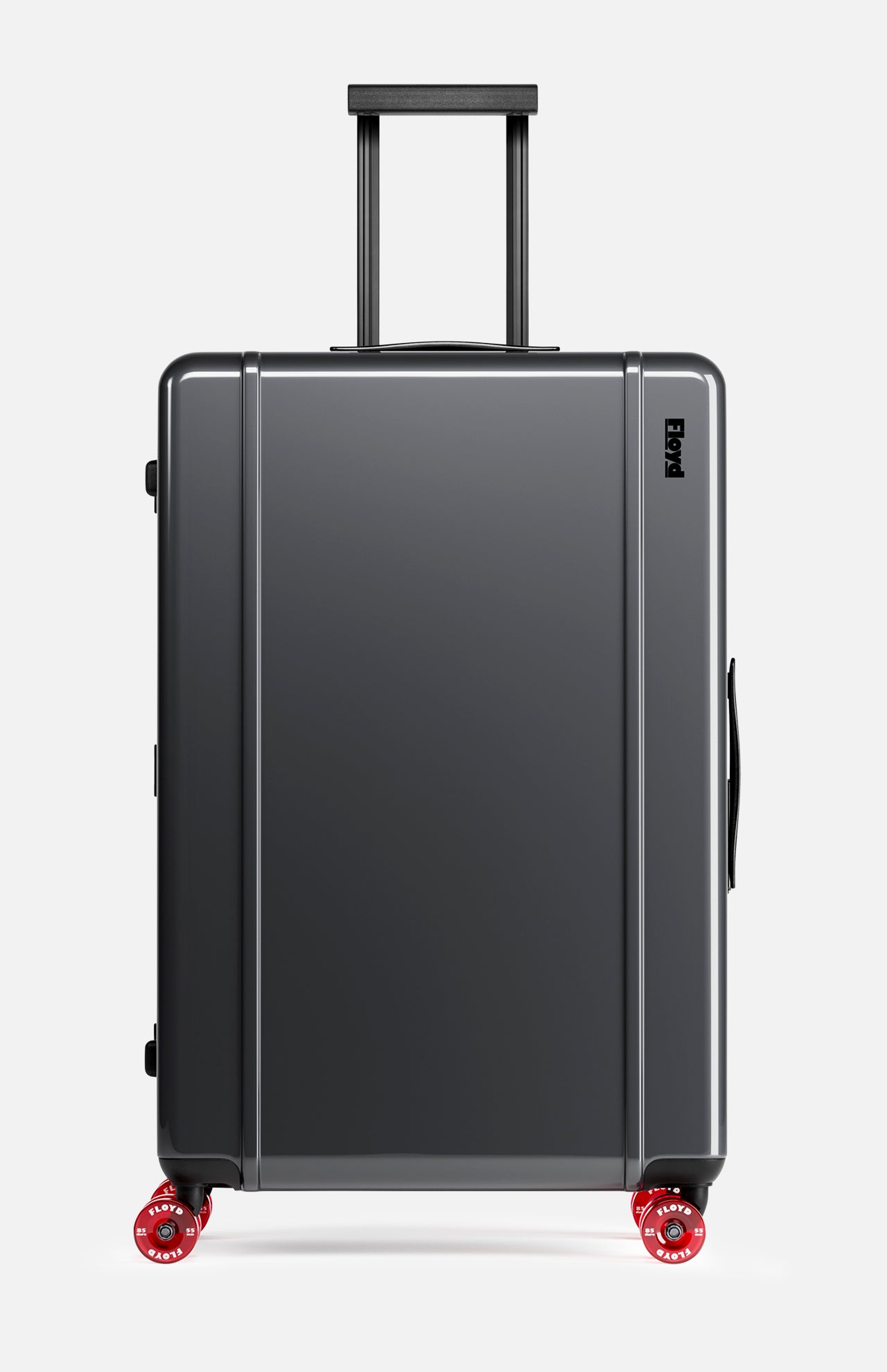 The Trunk Suitcase by FLOYD is a hard-top, dark gray suitcase featuring four red skateboard spinner wheels, a black side handle, and an extended black telescopic handle, displayed on a plain white background.