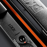 Close-up of a black TSA007 lock on The Trunk Suitcase by FLOYD, featuring the brand name embossed on the hard shell and an orange accent stripe.