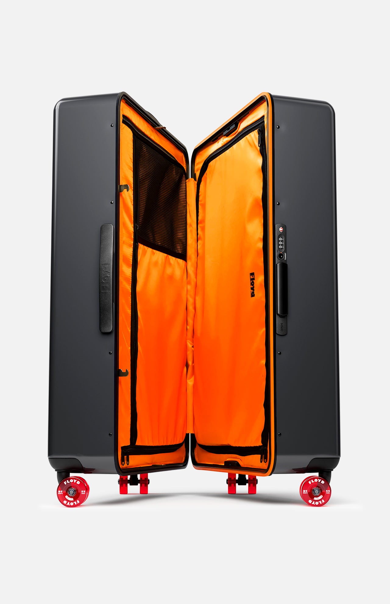 The Trunk Suitcase by FLOYD stands upright, open to display its vivid orange interior with mesh pockets and dividers. Shown on a white background, it features skateboard spinner wheels and a side handle.