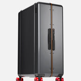 The Trunk Suitcase by FLOYD features a sleek black hard-top design with an orange accent stripe and stands upright on four transparent red skateboard spinner wheels against a plain light background.