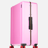 The Trunk Suitcase by FLOYD stands upright against a plain white background, featuring a large, glossy pink hard-top shell, black handle, TSA lock, and four red transparent 360° spinner wheels.