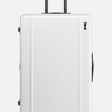 The Trunk Suitcase by FLOYD is a white hard-top check-in suitcase with black handles and four red skateboard spinner wheels, shown upright on a plain background. The FLOYD logo appears near the top right corner.
