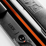 Close-up of a black lock with LOCK, a TSA007 keyhole, and part of a combination dial on the hard-top FLOYD The Trunk Suitcase; brand name is embossed on metal above orange trim.