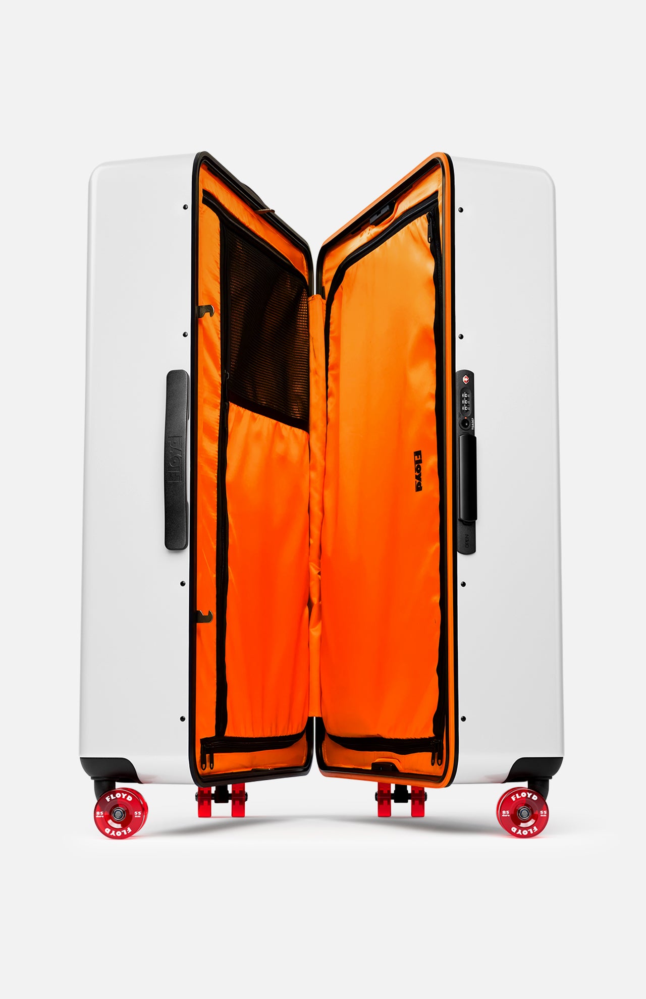 The Trunk Suitcase by FLOYD is a white hard-top check-in case with red skateboard spinner wheels, a sturdy black side handle, and an open bright orange interior featuring mesh pockets and black zippers.