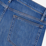 Close-up of the back pocket and waistband of the Frame L’Homme Slim Jean in Verdugo, highlighting the premium stretch denim’s visible stitching and belt loop. These dark blue jeans feature a subtle faded texture.