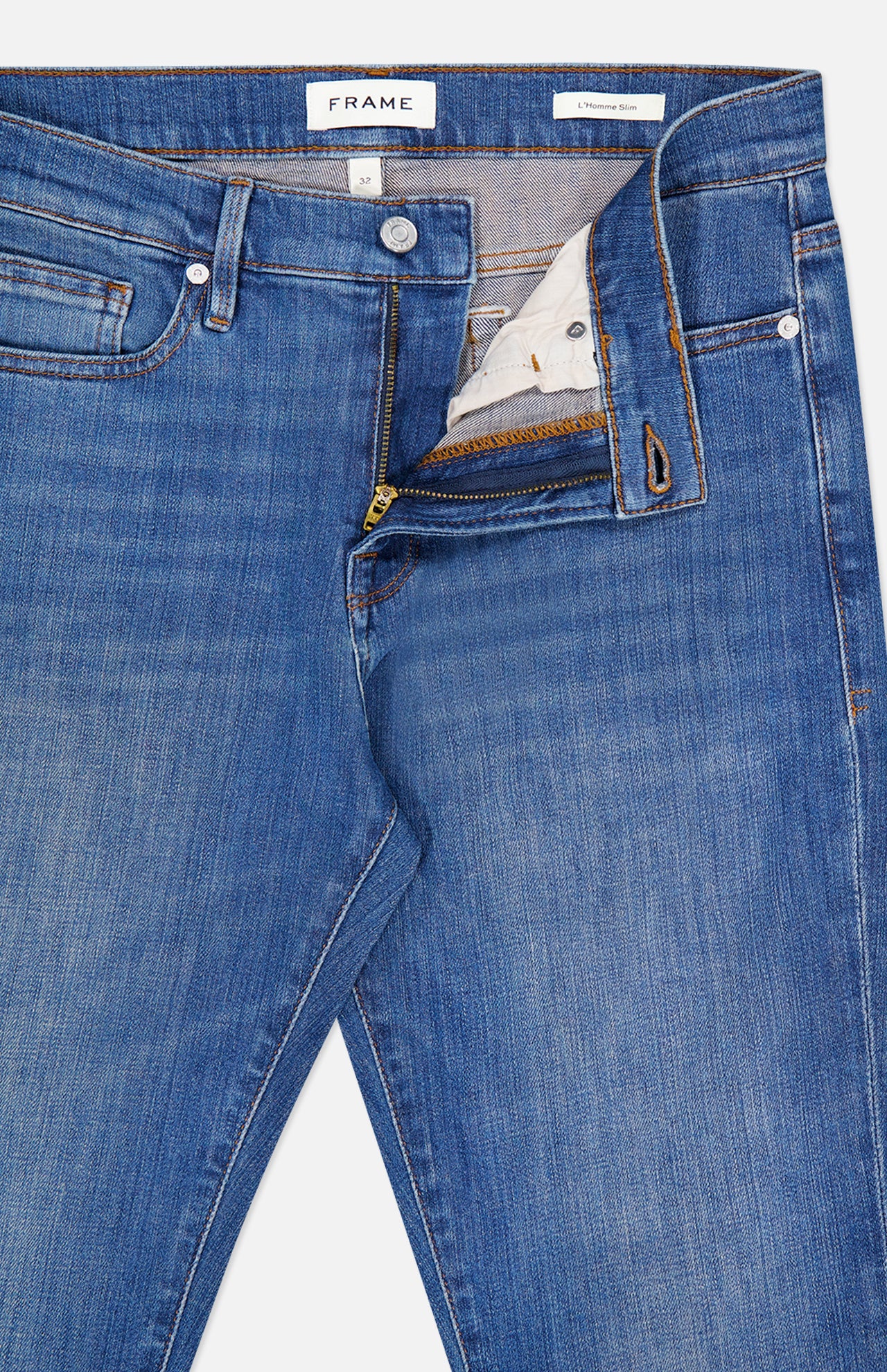 A pair of Frame L’Homme Slim Jeans in Verdugo, crafted from premium stretch denim in dark blue, featuring a slim fit silhouette with a partially open zipper and button fly that reveals the FRAME-branded waistband label.