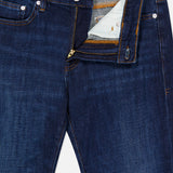 L’Homme Slim Jean in Baltic by Frame, crafted from premium stretch dark blue denim, features a partially open visible zipper fly revealing the inside lining and button. These slim fit jeans are detailed with copper stitching, silver rivets, and a FRAME label on the inside waistband.