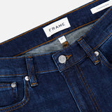 Close-up of the waistband and upper section of Frame’s L’Homme Slim Jean in Baltic, crafted from premium stretch denim in an ultra-dark blue wash. The image showcases the button, zipper, belt loops, brand label, and contrast stitching details that define this slim fit style.