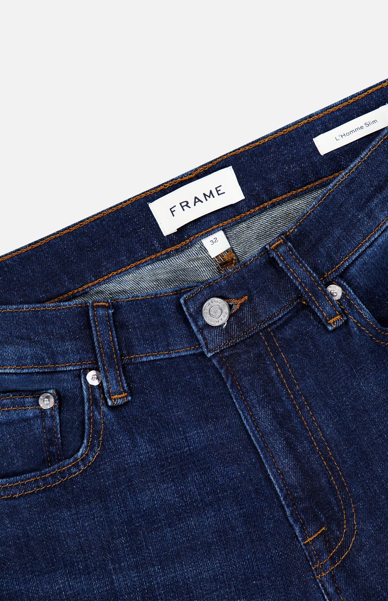 Close-up of the waistband and upper section of Frame’s L’Homme Slim Jean in Baltic, crafted from premium stretch denim in an ultra-dark blue wash. The image showcases the button, zipper, belt loops, brand label, and contrast stitching details that define this slim fit style.