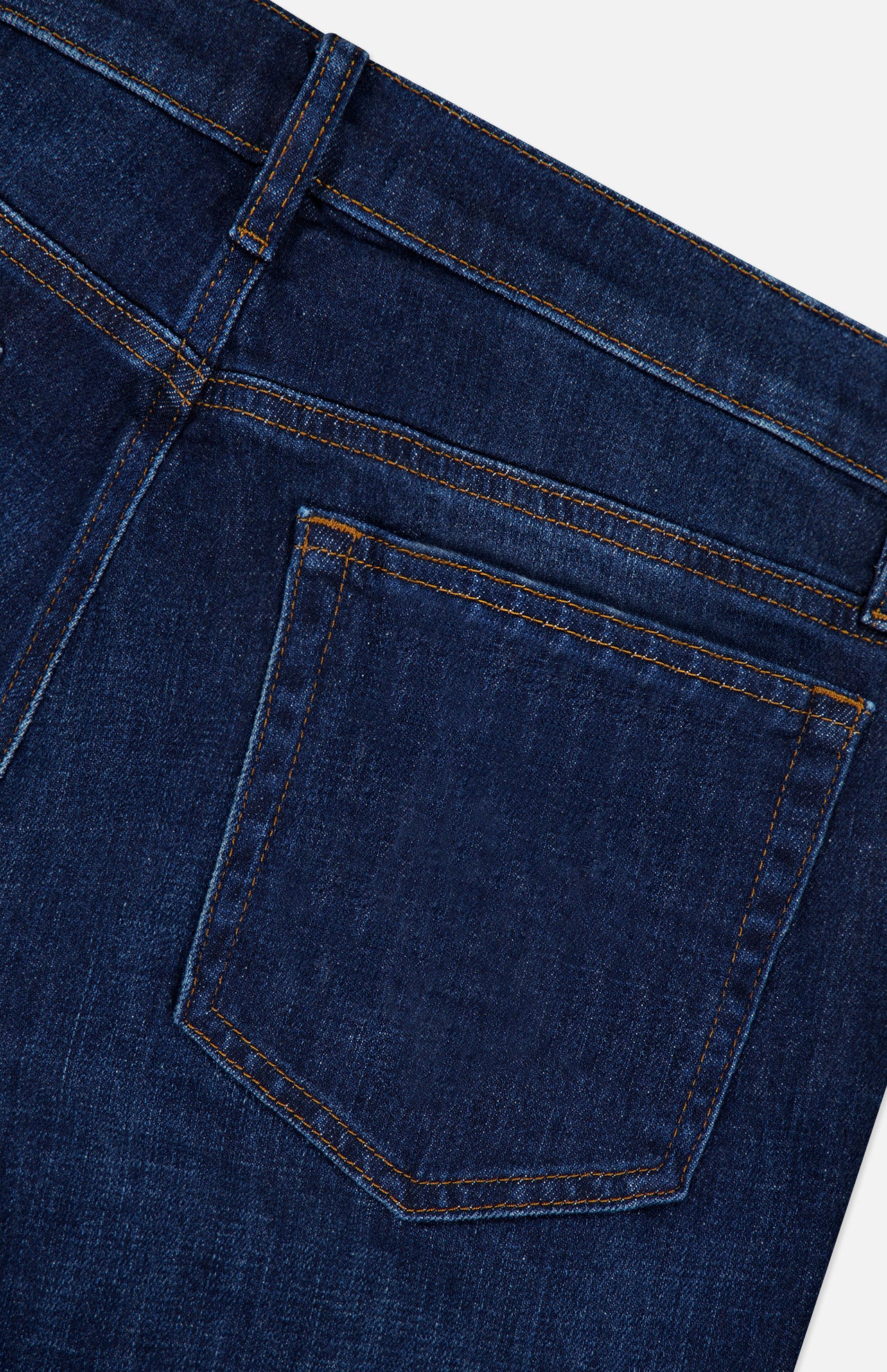 Close-up of the back pocket of the Frame L’Homme Slim Jean in Baltic, highlighting the stitching details along with a portion of the waistband and belt loop. Crafted from premium stretch denim, the fabric appears new and unworn.