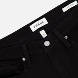Close-up of the FRAME L’Homme Slim Pant in Noir, featuring a black denim design with a branded FRAME label on the waistband, silver button closure, front pocket, and a small tag reading “L’Homme Slim.” Crafted from premium stretch denim, these slim fit jeans combine modern style with exceptional comfort.