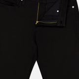 L’Homme Slim Pant in Noir by Frame, crafted from stretch denim, features a partially open zipper and unbuttoned waistband that reveals the inside label and pocket details. Designed in a modern slim fit for a sleek silhouette.