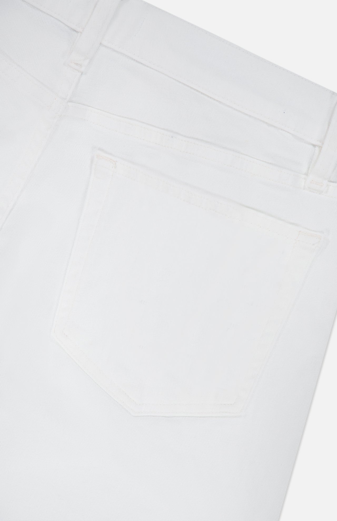 Close-up of the back pocket and waistband of the L’Homme Slim Pant in Whisper White by Frame, crafted from premium stretch denim and featuring detailed stitching.