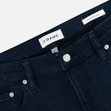 The Modern Straight Pant in Placid by Frame is crafted from comfort stretch denim in a dark blue wash, featuring silver buttons and rivets, belt loops, and visible FRAME and Modern Straight tags inside the waistband, shown on a plain white background.
