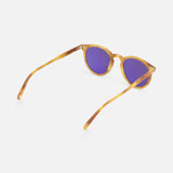 The GARRETT LEIGHT Carlton Round Tan Sunglasses feature purple-tinted lenses and bio-based acetate frames, displayed at an angle with open arms on a white background.