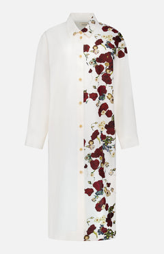 The KHAITE Gloria Cocoon Shape Dress is a white, long-sleeved silk-cotton dress with a collar and button-down front. It showcases a bold red floral pattern on one side, offering a modern twist on the classic floral print dress.