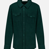 The Solid Cashmere Shirt with Malachite Buttons by God’s True Cashmere is a dark green unisex button-up featuring long sleeves, a pointed collar, adjustable cuffs, and two chest pockets with flaps and malachite buttons. Expertly crafted from soft cashmere for a luxurious feel, it is displayed against a plain white background.