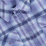 Close-up of a blue and purple plaid cashmere shirt by God’s True Cashmere. This unisex Plaid Cashmere Shirt with Amethyst Button features eye-catching amethyst gemstone snaps and chest pockets, elevating the classic blue plaid design with luxurious detail.