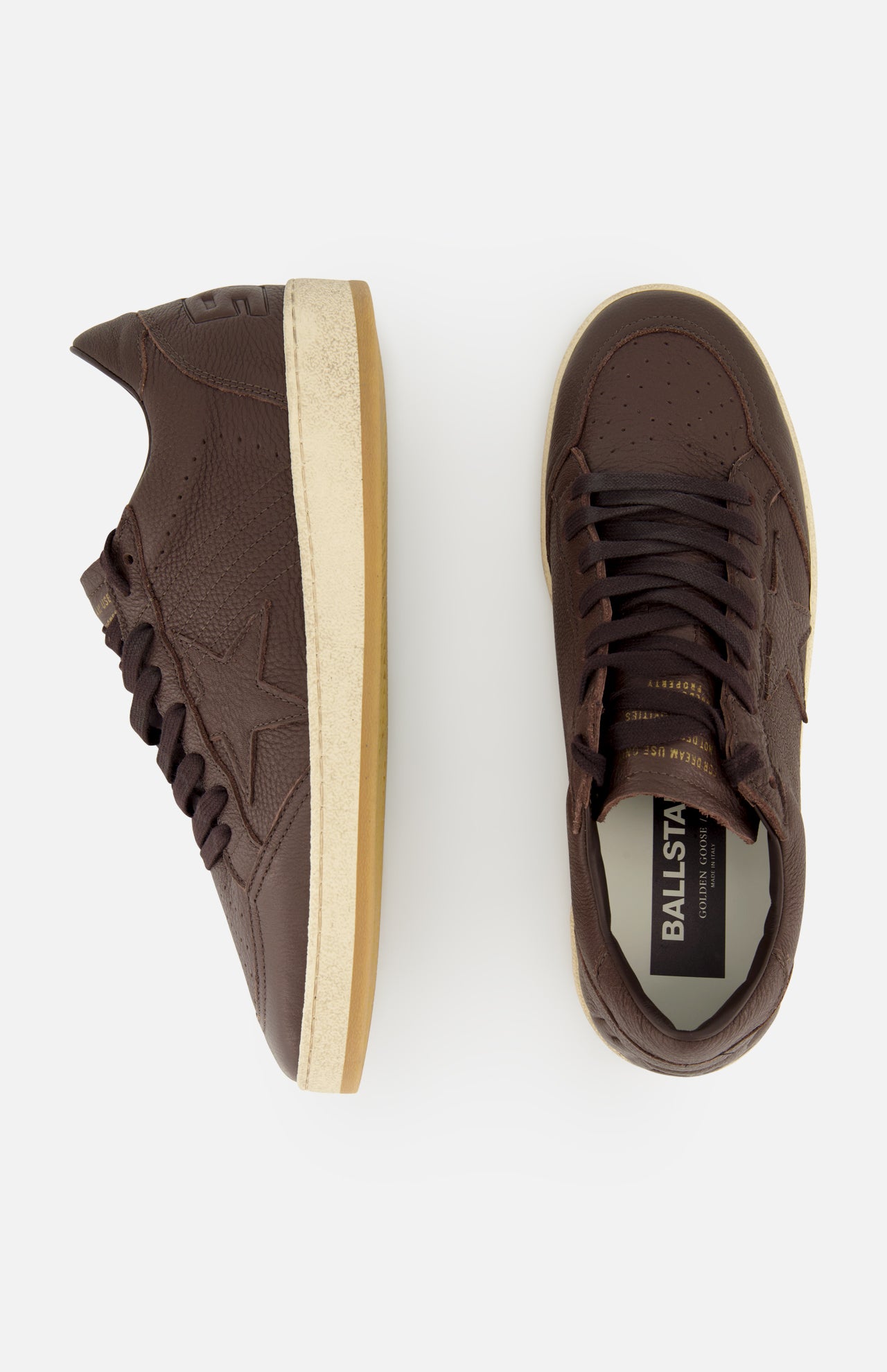 A pair of GOLDEN GOOSE Ballstar Leather Upper Sneakers in dark brown leather with white rubber soles is shown from side and top views, featuring perforated toe detailing, a subtly distressed sole, and BALLSTAR branding on the insole.