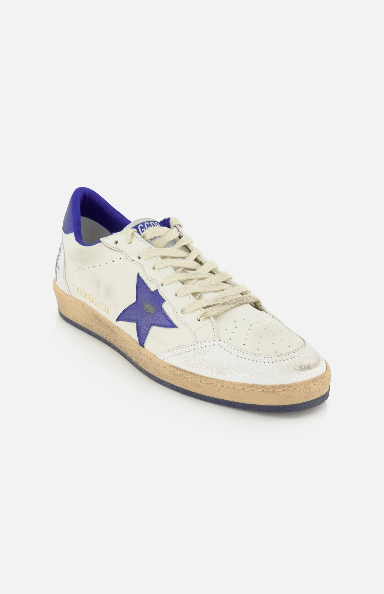 A GOLDEN GOOSE Ballstar Nappa Upper Sneaker in white leather features a blue star on the side, a scuffed sole, cream laces, and a blue heel detail in the brand’s signature style, photographed against a white background.
