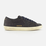 Introducing the Super Star Leather Upper Sneaker by GOLDEN GOOSE—a black low-top crafted with a signature star detail on the side. This standout sneaker showcases a white distressed sole for a worn-in vibe and displays GGDB/SSSTAR in gold lettering near the heel. Ideal for fans of navy-inspired sneakers who appreciate iconic Golden Goose styling and eye-catching details.