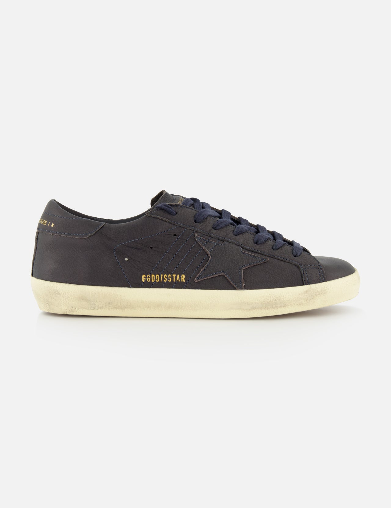 Introducing the Super Star Leather Upper Sneaker by GOLDEN GOOSE—a black low-top crafted with a signature star detail on the side. This standout sneaker showcases a white distressed sole for a worn-in vibe and displays GGDB/SSSTAR in gold lettering near the heel. Ideal for fans of navy-inspired sneakers who appreciate iconic Golden Goose styling and eye-catching details.