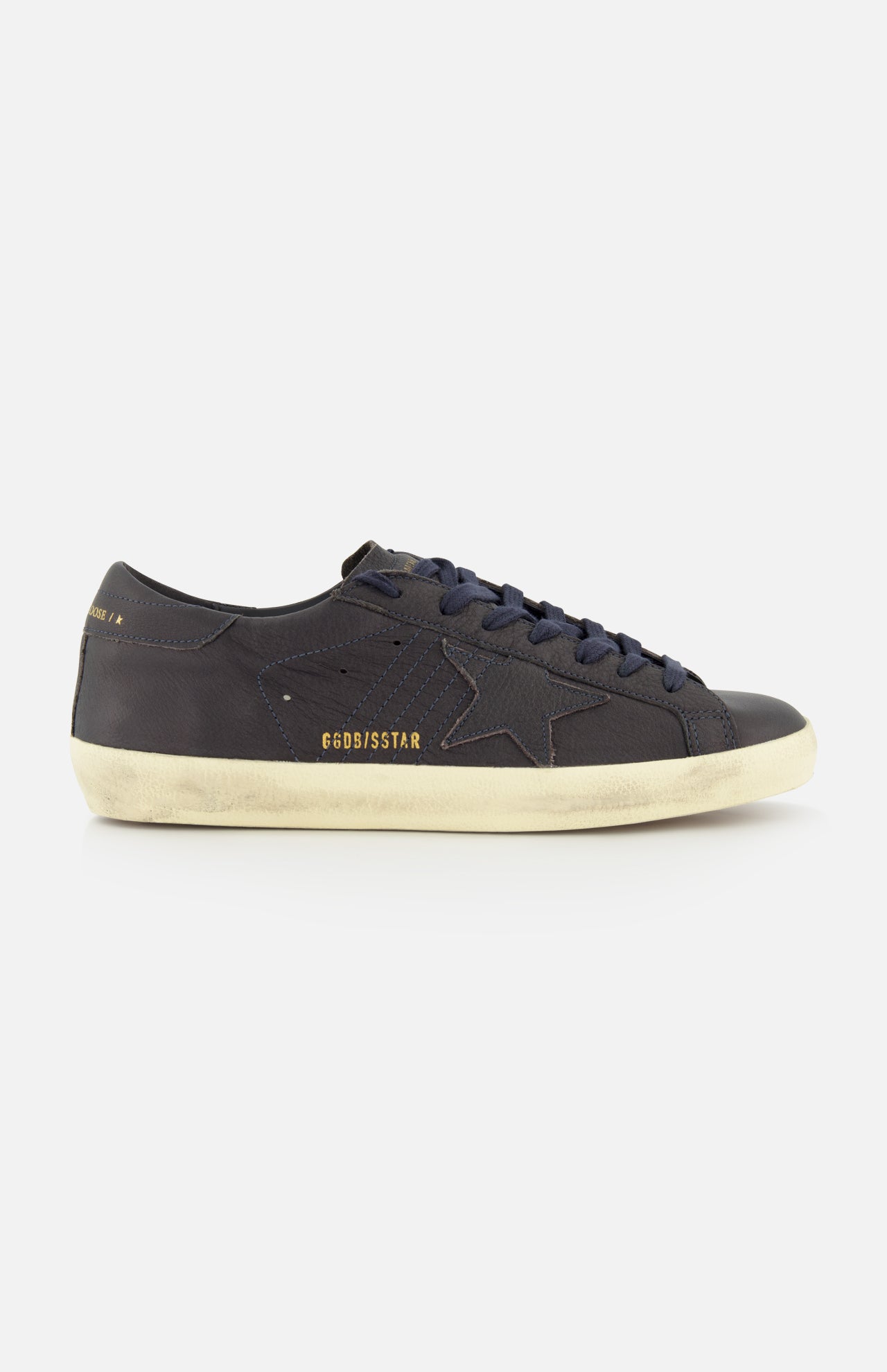 Introducing the Super Star Leather Upper Sneaker by GOLDEN GOOSE—a black low-top crafted with a signature star detail on the side. This standout sneaker showcases a white distressed sole for a worn-in vibe and displays GGDB/SSSTAR in gold lettering near the heel. Ideal for fans of navy-inspired sneakers who appreciate iconic Golden Goose styling and eye-catching details.