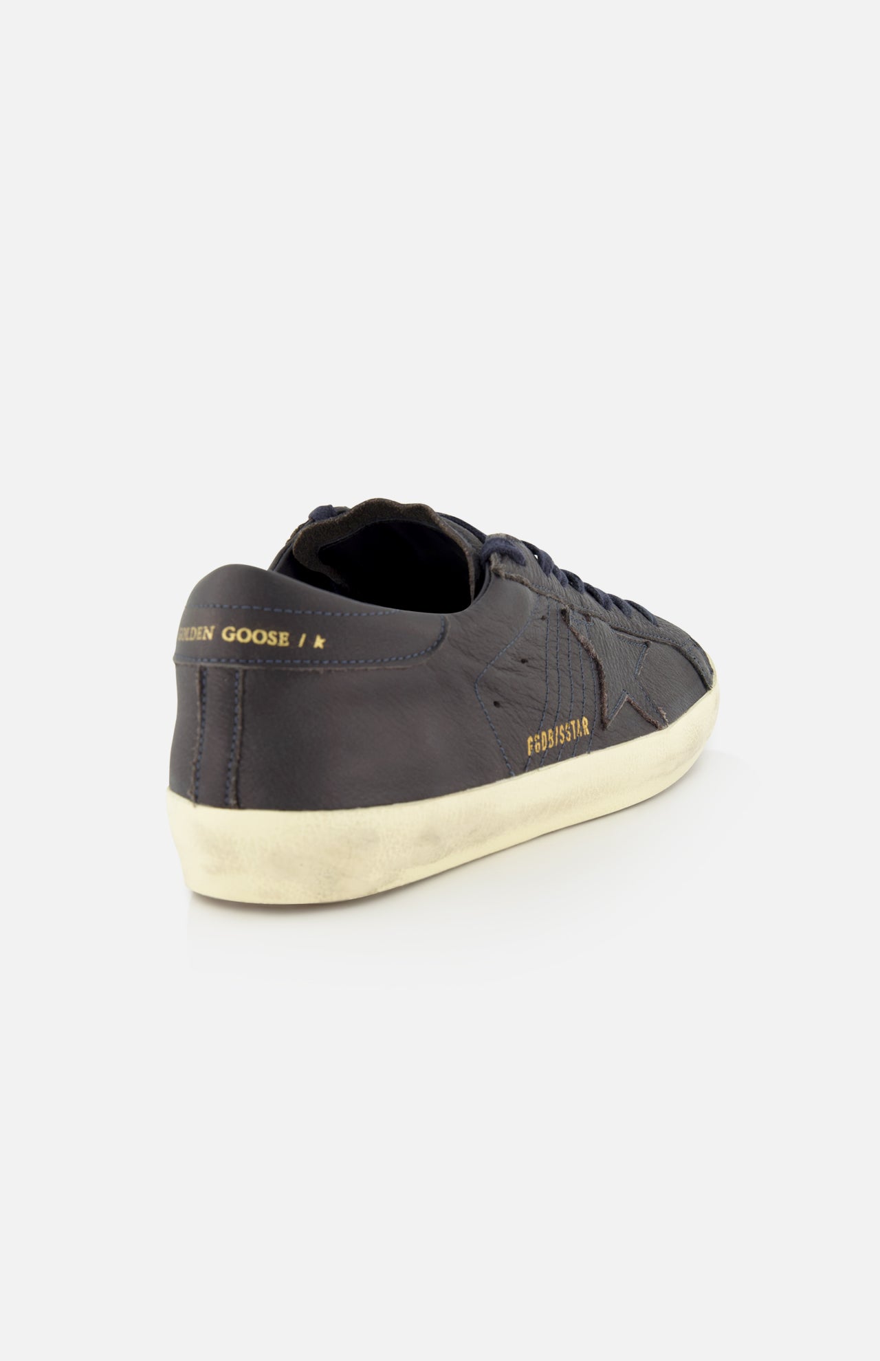 The Super Star Leather Upper Sneaker by GOLDEN GOOSE is shown from the back left angle against a white background, featuring a dark navy leather upper, a distressed sole, gold "GOLDEN GOOSE" text near the heel, and a star design on the side.
