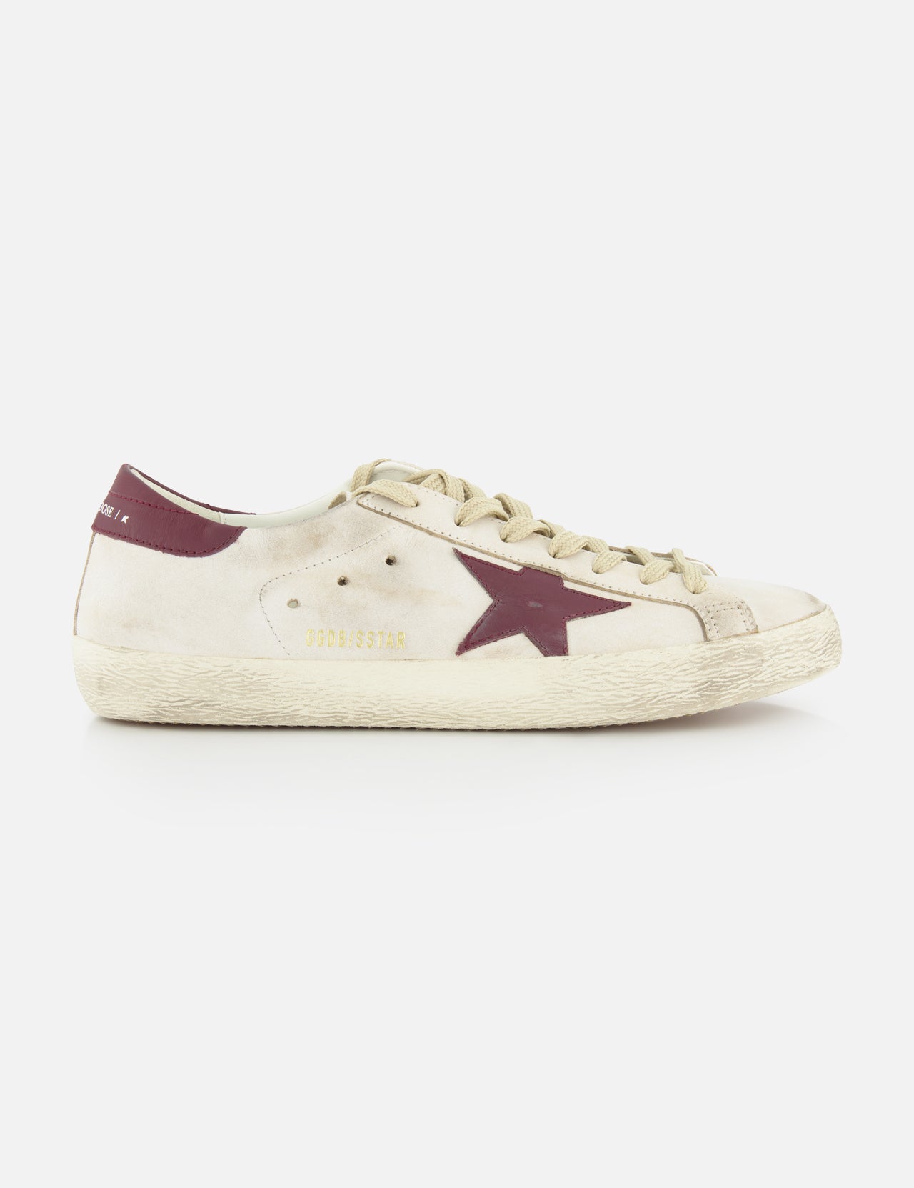 The GOLDEN GOOSE Super Star Leather Upper Toe And Tongue Sneaker features an off-white leather lace-up design with beige laces, a maroon star detail, GOLDENSTAR in gold, scuff marks, and a maroon heel tab for a signature distressed look.