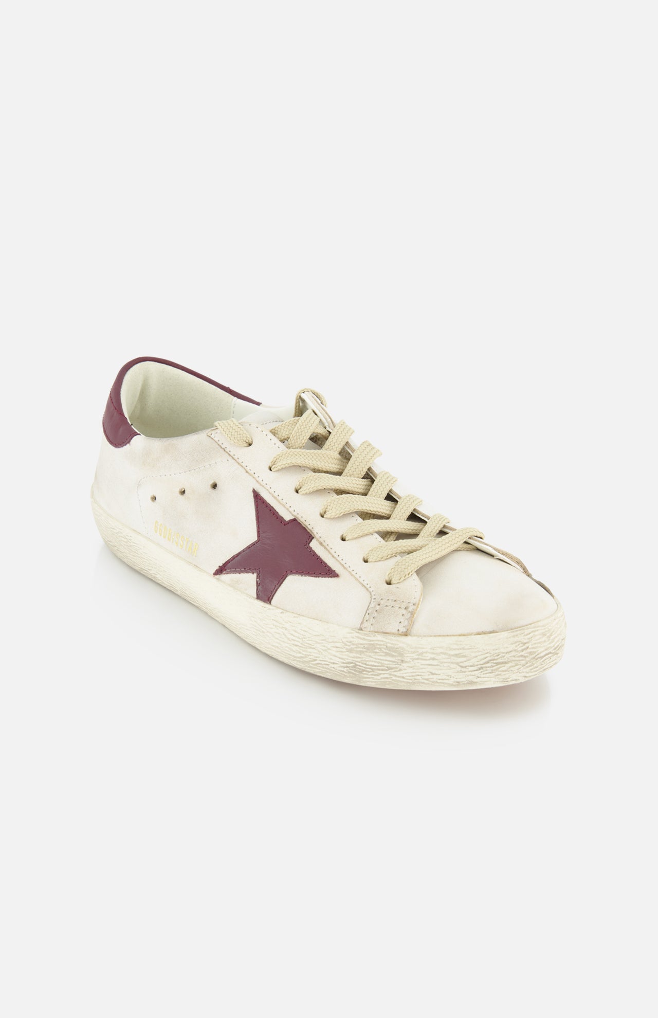 The GOLDEN GOOSE Super Star Leather Upper Toe And Tongue Sneaker features beige laces, a worn-in look, and a dark red star on the side, capturing the classic style against a plain white background.