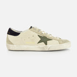 The GOLDEN GOOSE Super Star Nappa Upper Suede Sneaker features a beige upper, green side star, white laces, black heel tab, and a worn, distressed sole.