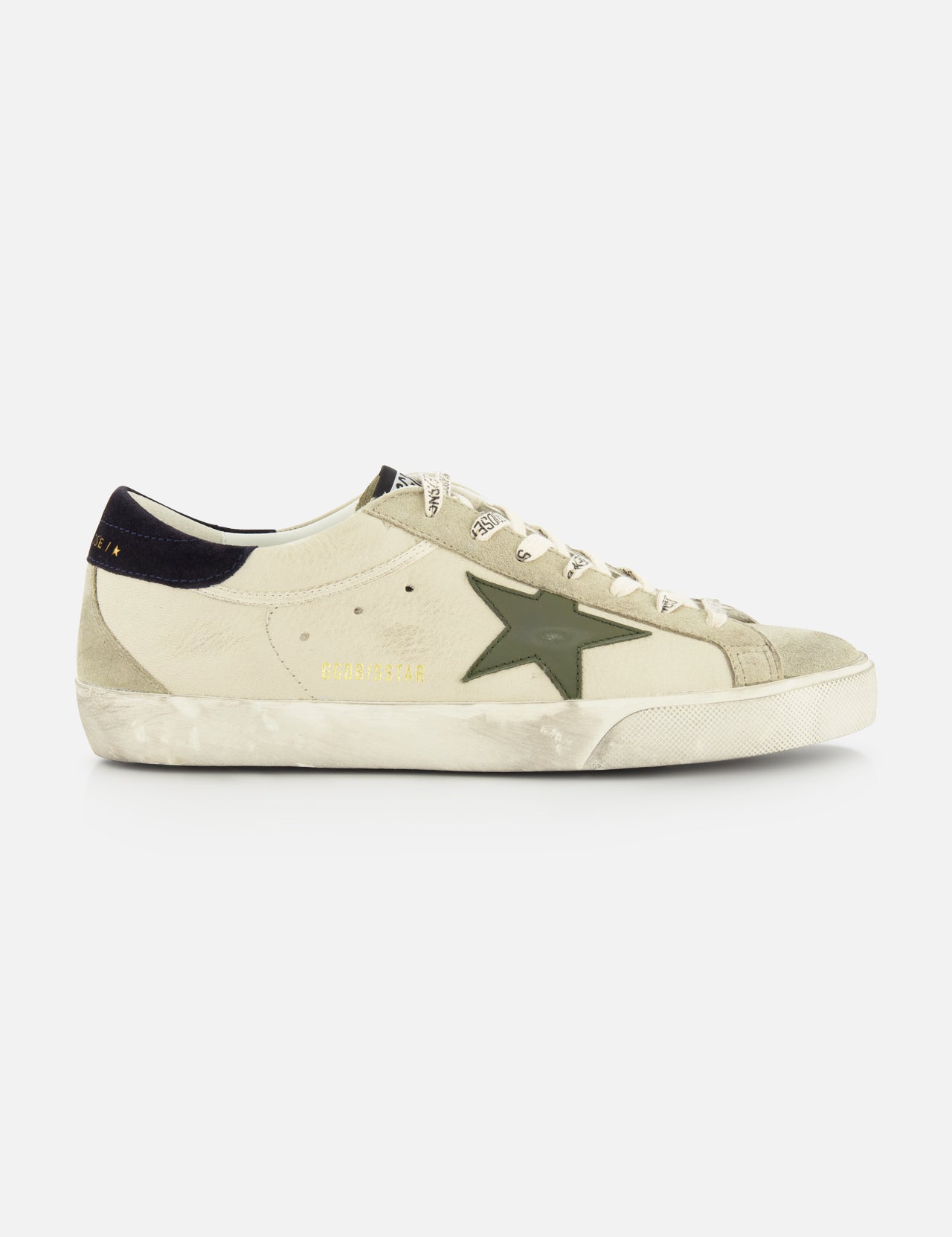 The GOLDEN GOOSE Super Star Nappa Upper Suede Sneaker features a beige upper, green side star, white laces, black heel tab, and a worn, distressed sole.