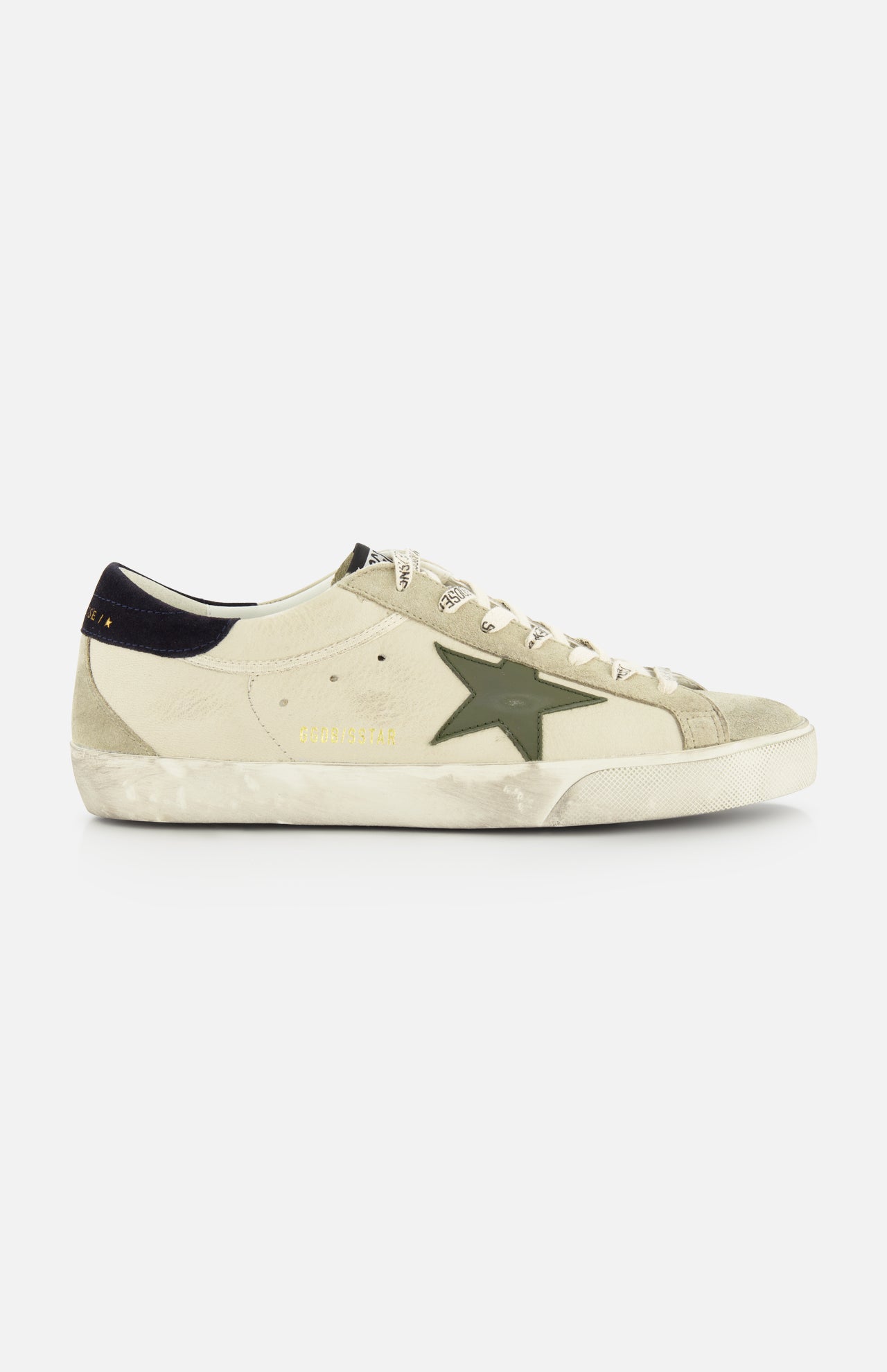 The GOLDEN GOOSE Super Star Nappa Upper Suede Sneaker features a beige upper, green side star, white laces, black heel tab, and a worn, distressed sole.