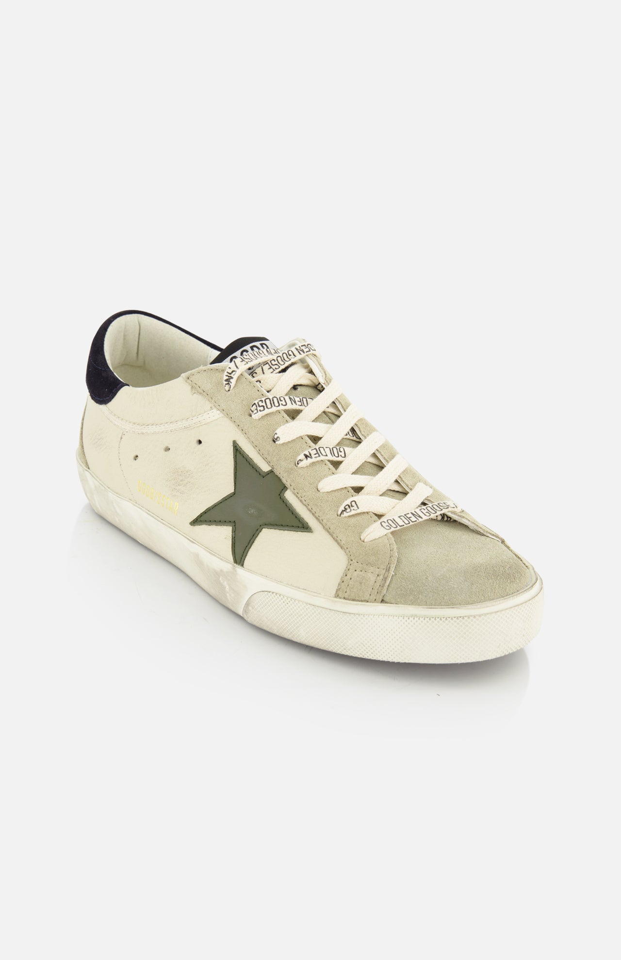 The Super Star Nappa Upper Suede Sneaker by GOLDEN GOOSE features a beige and light grey leather upper, green star detail, white laces with branding, a white sole, dark heel tab, and a softly worn vintage-inspired finish.