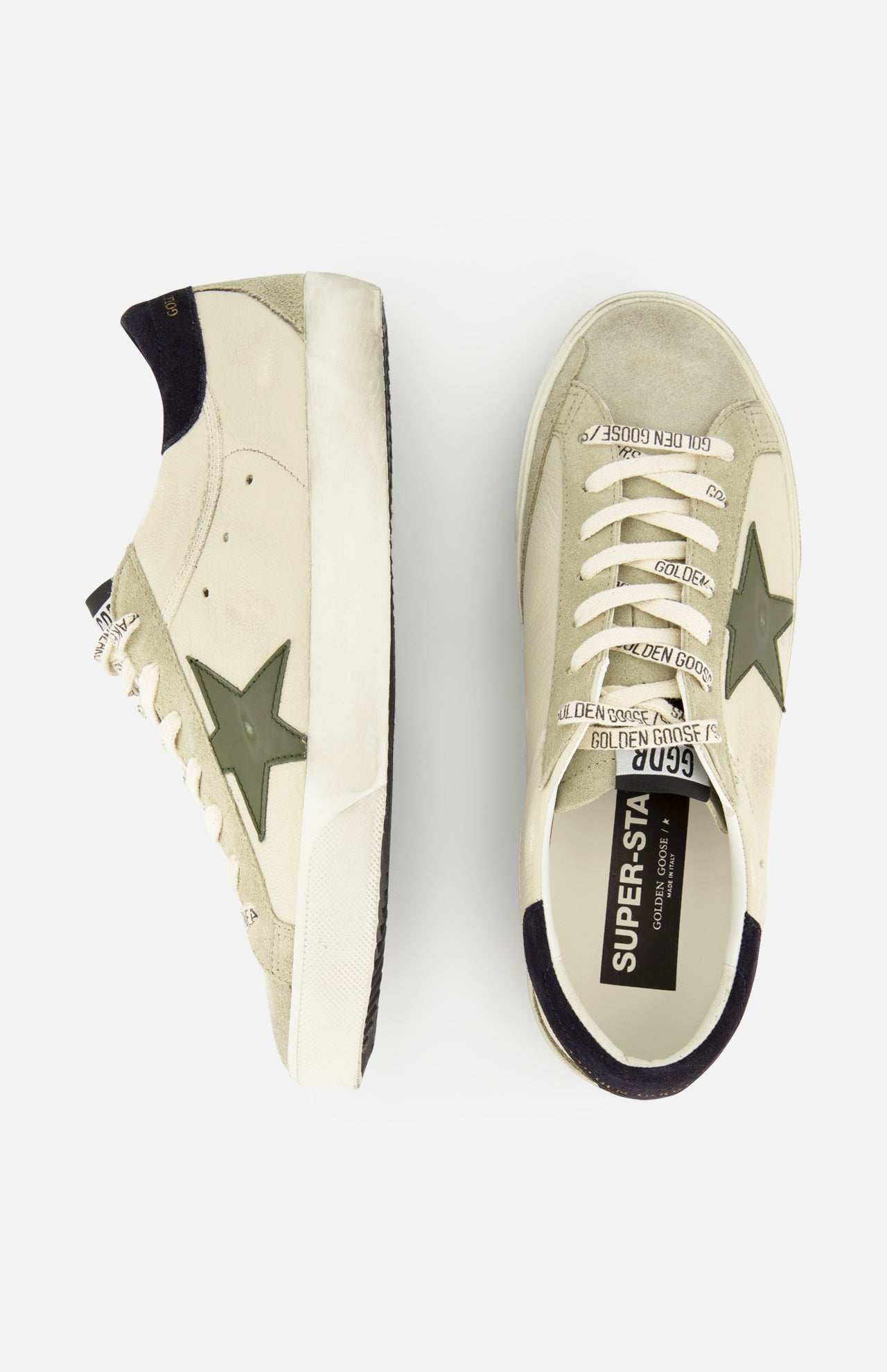 The GOLDEN GOOSE Super Star Nappa Upper Suede Sneakers feature a beige design with olive green stars, black heel patches, white soles, and laces printed with “GOLDEN GOOSE.” One light grey leather sneaker is shown from the side and one from above.