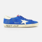 The GOLDEN GOOSE Super Star Suede Upper And Nylon Tongue Sneaker features blue suede, white laces, a white star detail, and an off-white sole with "Golden Goose" in black. Its purposely distressed look adds casual style.