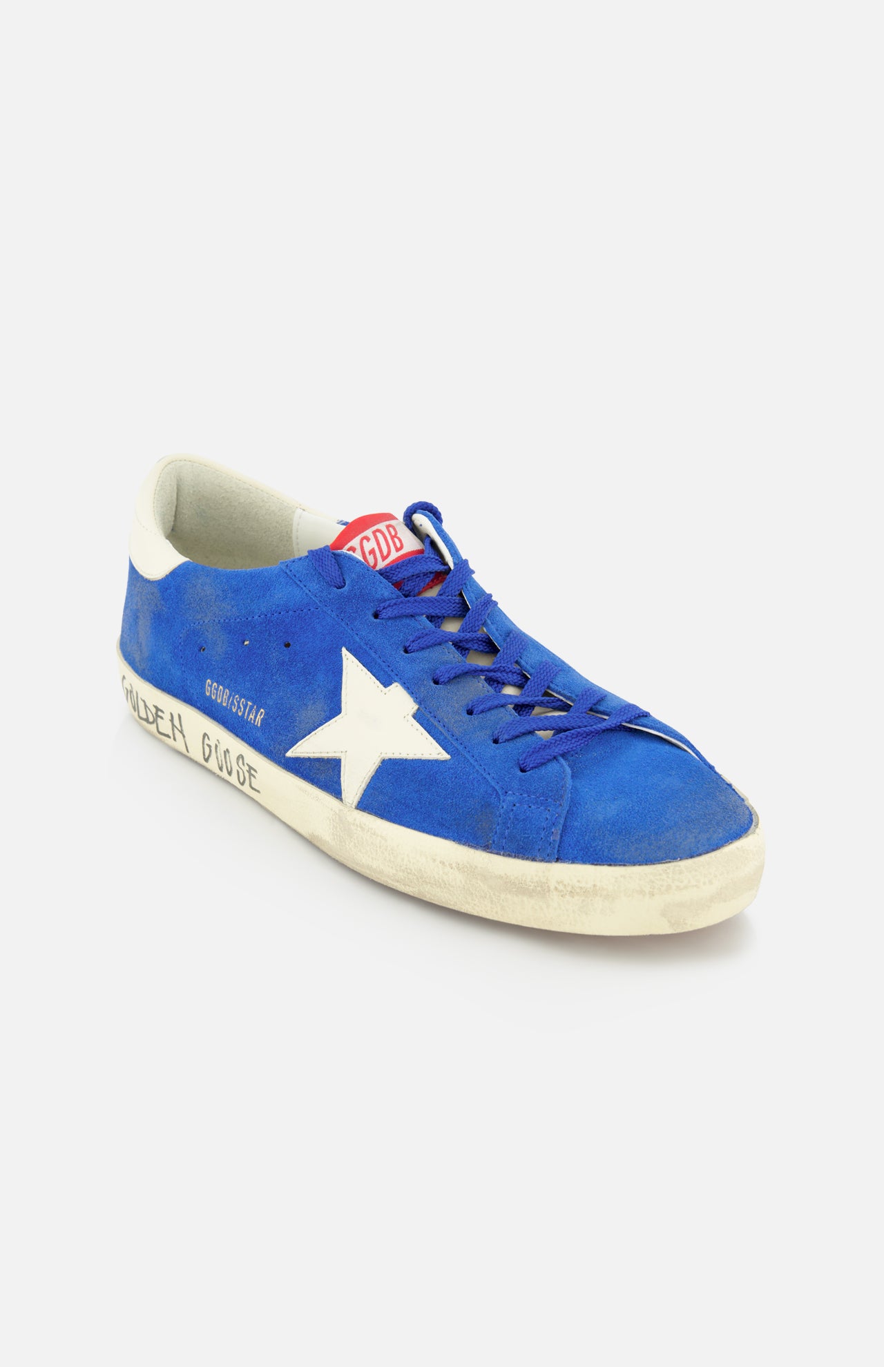 The GOLDEN GOOSE Super Star Suede Upper And Nylon Tongue Sneaker features a blue suede upper, white star, worn-effect white sole, and GOLDEN GOOSE branding on the side and tongue, with blue laces adding classic style.