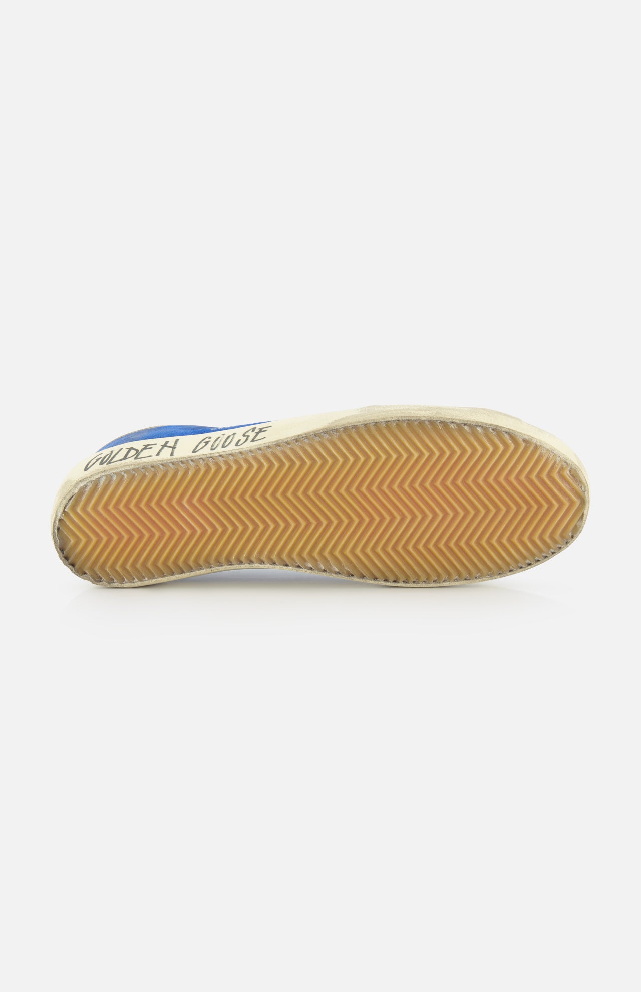 The image shows the sole of a GOLDEN GOOSE Super Star Suede Upper And Nylon Tongue Sneaker, with a tan rubber herringbone tread. The leather lace-up shoe’s side displays “GOLDEN GOOSE” in blue text on white.