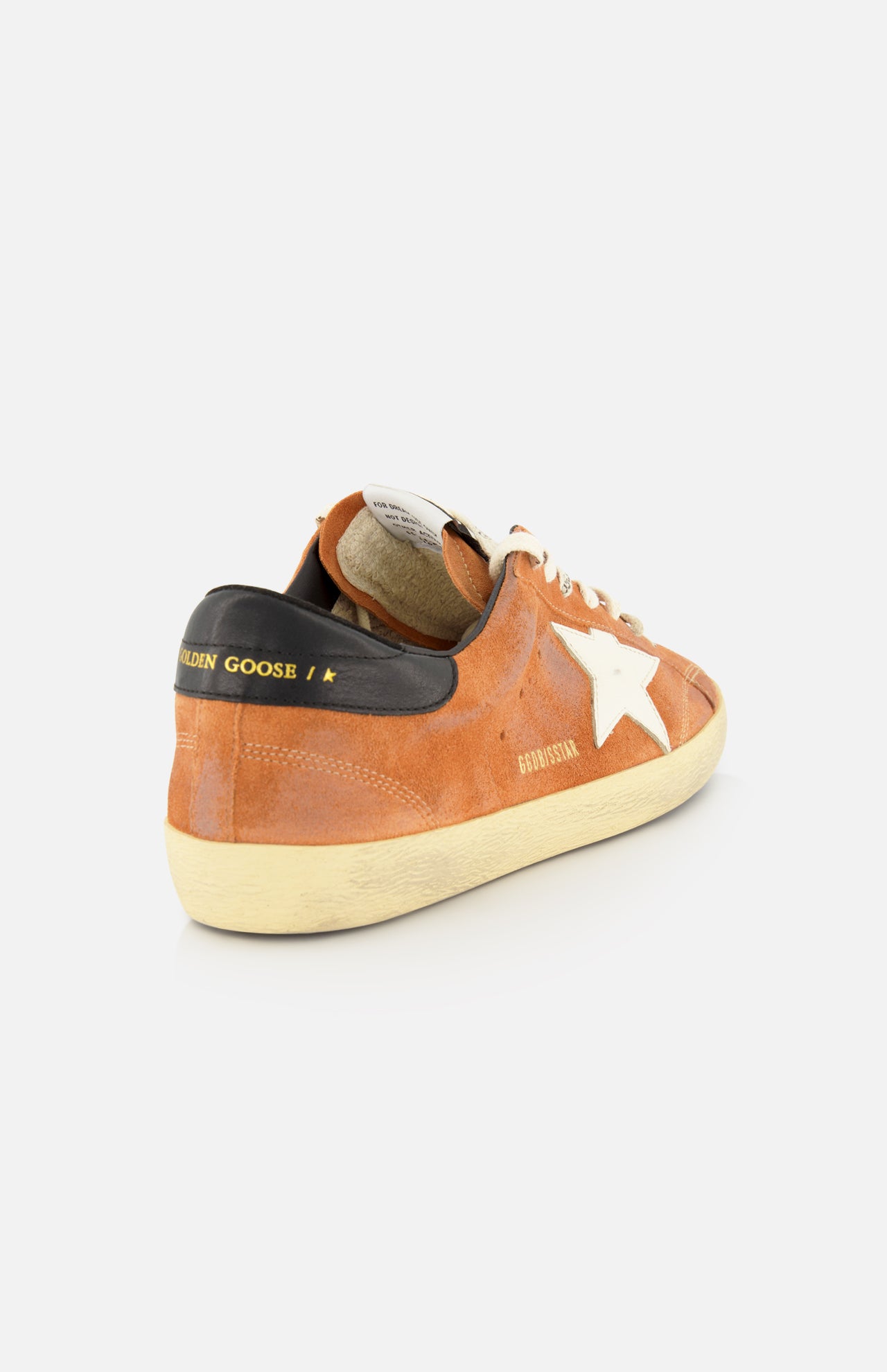 The GOLDEN GOOSE Super Star Suede Upper Toe And Tongue Sneaker features a brown suede upper, a distinctive white star accent on the side, beige laces, and a black heel tab with bold yellow text. Its signature scuffed sole completes the look, all showcased against a plain white background.