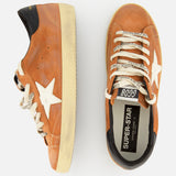 A pair of GOLDEN GOOSE Super Star Suede Upper Toe And Tongue Sneakers in tan, featuring white stars, black heel tabs, and cream-colored laces. The sneakers are finished with the brand's signature scuffed sole for a distinctive look. One shoe is shown from the side while the other is viewed from above, revealing "SUPER-STAR" on the insole.