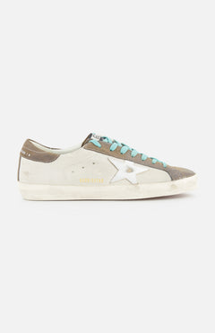 The GOLDEN GOOSE Super-Star Leather And Laminated Star Sneaker features beige, brown, and gray panels, turquoise laces, a white star detail, a distressed white sole, and “GGDB/STAR” gold lettering for signature style.