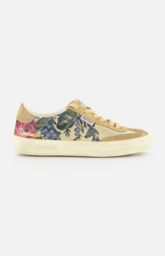 The GOLDEN GOOSE Soul-Star Canvas Sneaker features a beige canvas upper, tan laces and sole, and a botanical print with blue, purple, and pink flowers. Retro style with visible brand tags adds a signature touch.