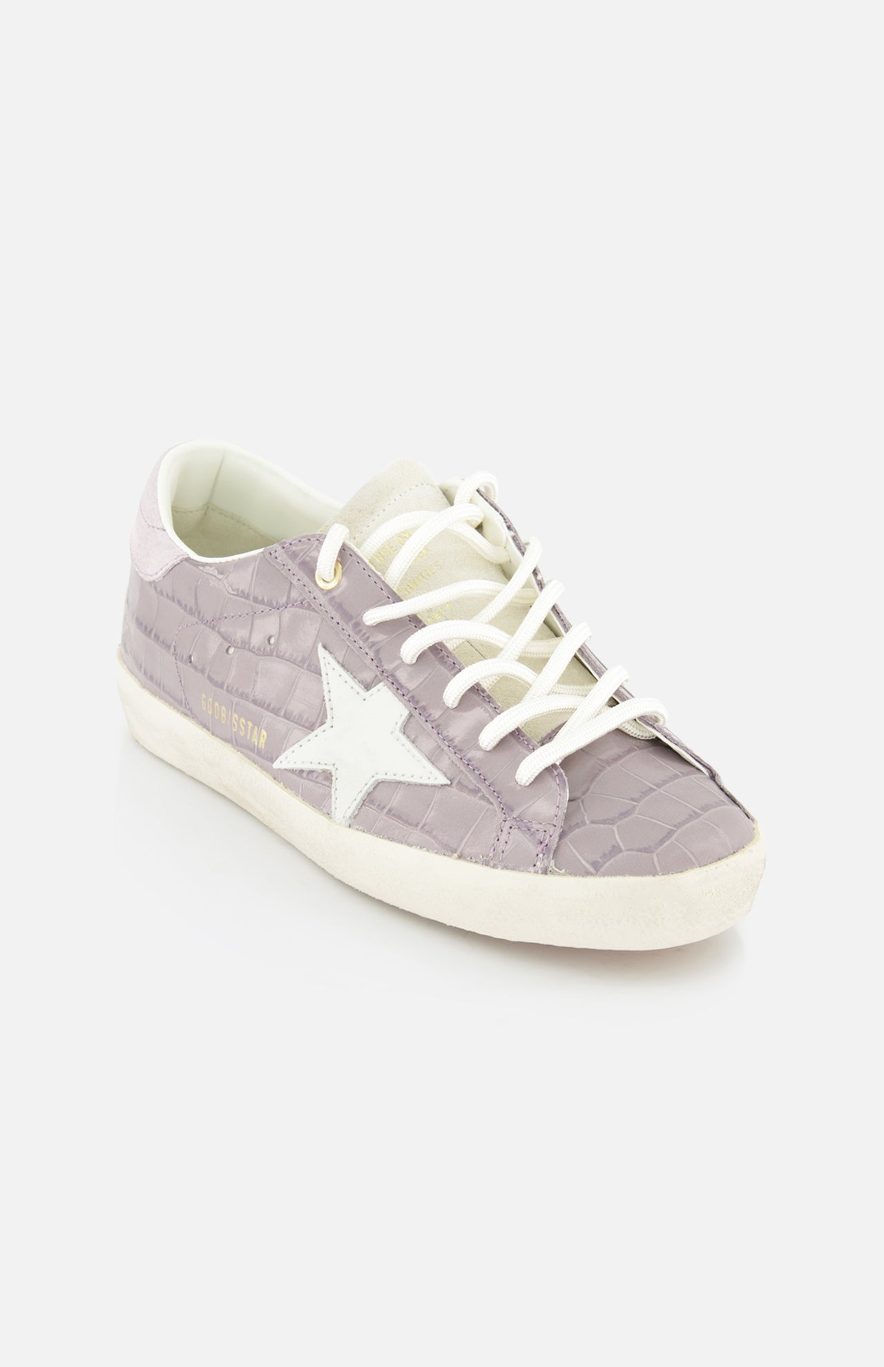 The GOLDEN GOOSE Super Star Crocco Printed Sneaker features a lilac crocodile-textured pattern, white laces, a white star logo on the side, and a light beige sole, shown against a plain white background.