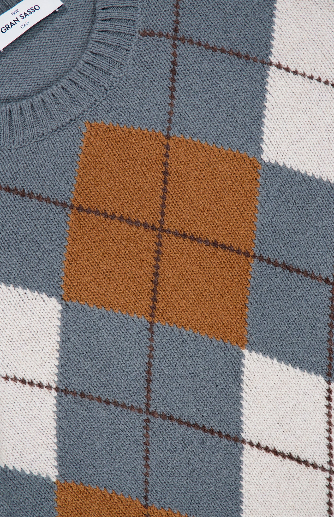 Close-up of the GRAN SASSO Argyle Pattern Crewneck Sweater, crafted from soft virgin wool and made in Italy. This sweater features an argyle pattern with shades of gray, mustard yellow, white, and brown. It is finished with a ribbed neckline and intersecting diagonal lines that form classic diamond shapes.