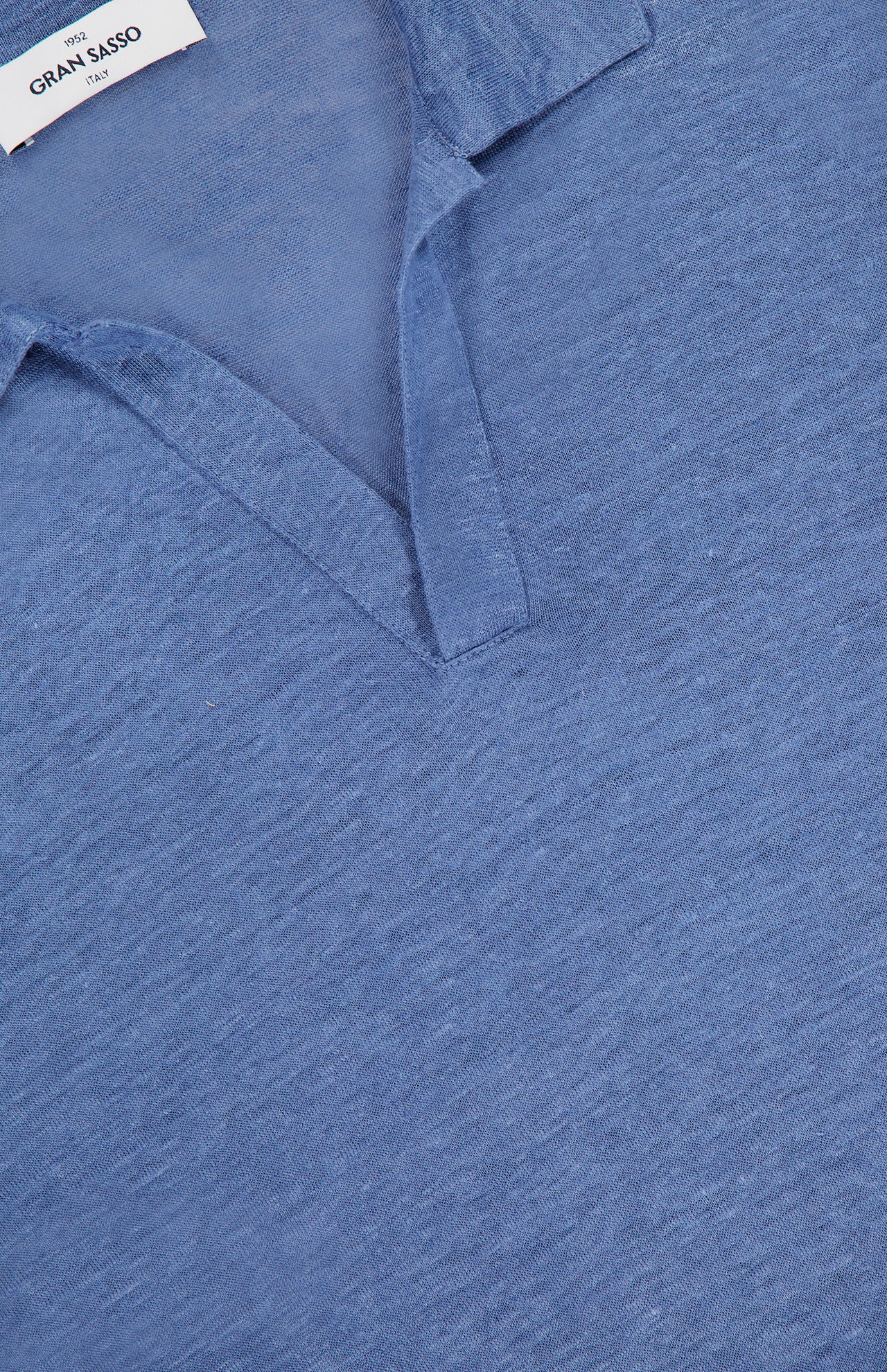 Close-up of the GRAN SASSO Johnny Collar Long Sleeve Polo Shirt in light blue, crafted from soft, textured fabric with a relaxed, buttonless Johnny collar and a white GRAN SASSO label at the inside collar. Inspired by classic navy linen polos.