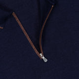 Close-up of a navy blue GRAN SASSO Quarter Zip Polo Sweater featuring a brown quarter-zip with a metal zipper pull, highlighting the collar and neck label. Expertly crafted in Italy, this sweater showcases refined craftsmanship and luxurious comfort.